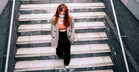 Woman wearing mask and walking down stairs