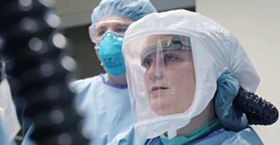 Two nurses wearing protective gowns and page coverings working