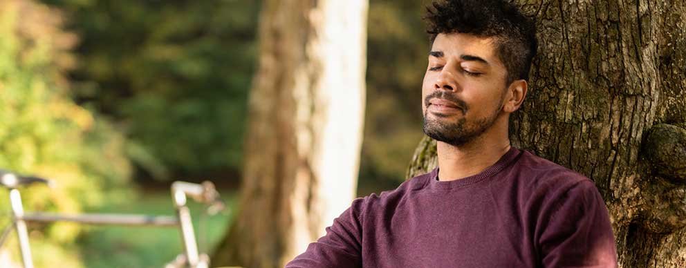 Image of man leaning against a tree