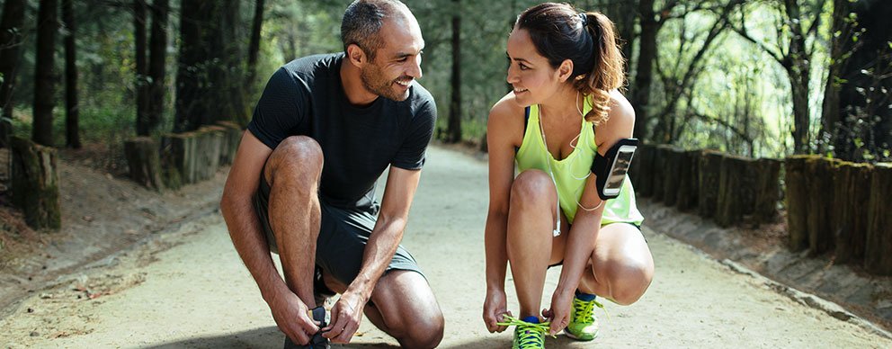 Man and woman kneeling down to tie shoes