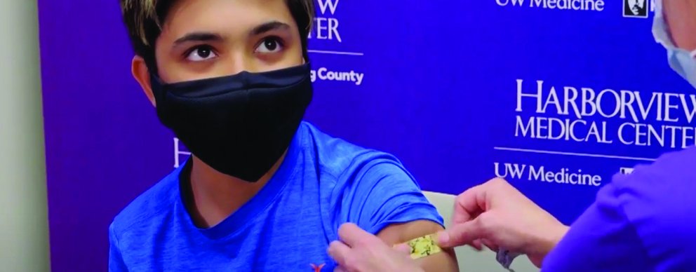 Provider putting a band aid on the arm of a boy who just received a COVID vaccine