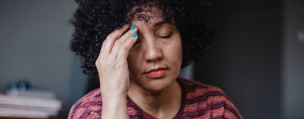 Woman closing her eyes and holding a hand to her forehead